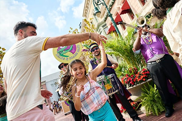 A father and daughter dance to music from the Beads & Brass band at Universal Mardi Gras: International Flavors of Carnaval.