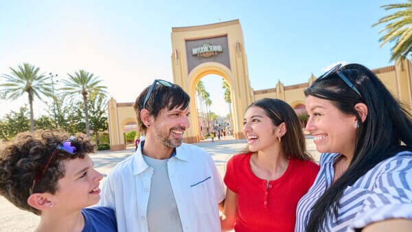 A family smile and embrace as they stand in front of the Universal Studios Florida arches.
