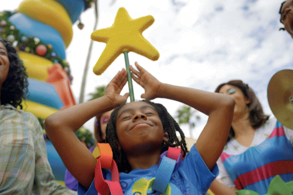 The Grinch dressed as Santa making an excited expression as people stand in the background.Adventure.