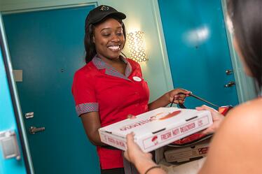 A woman delivers a pizza to a guest at Universal Orlando.