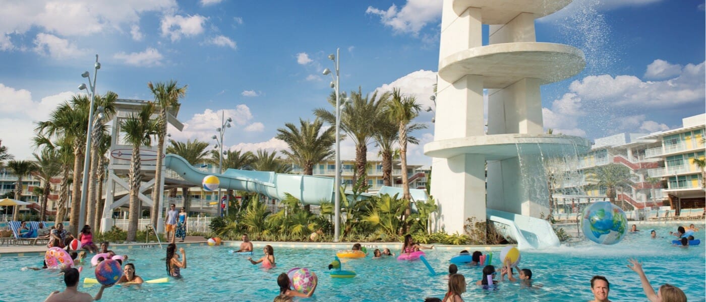 Guests playing and swimming by the water slide at the Cabana Courtyard pool, one of two large pools at Cabana Bay Beach Resort in Universal Orlando.
