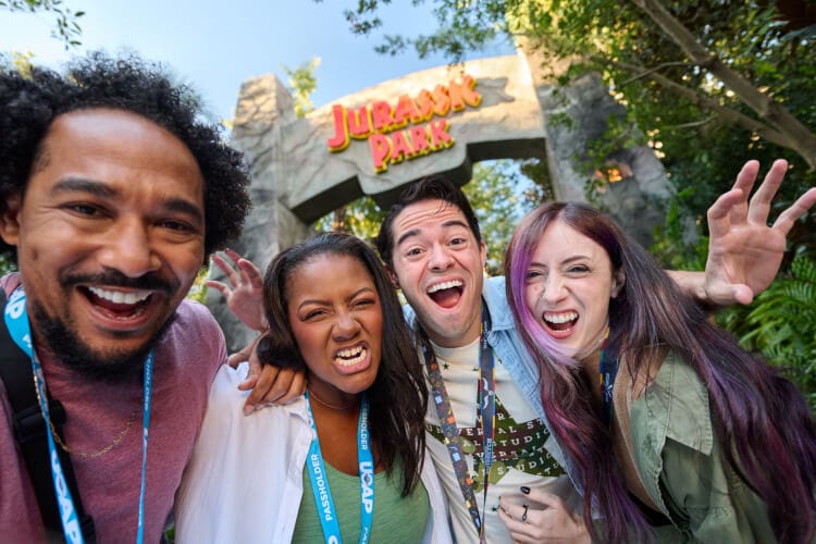 A group of Universal Orlando Annual Passholders pose for a selfie in front of the Jurassic Park entrance.