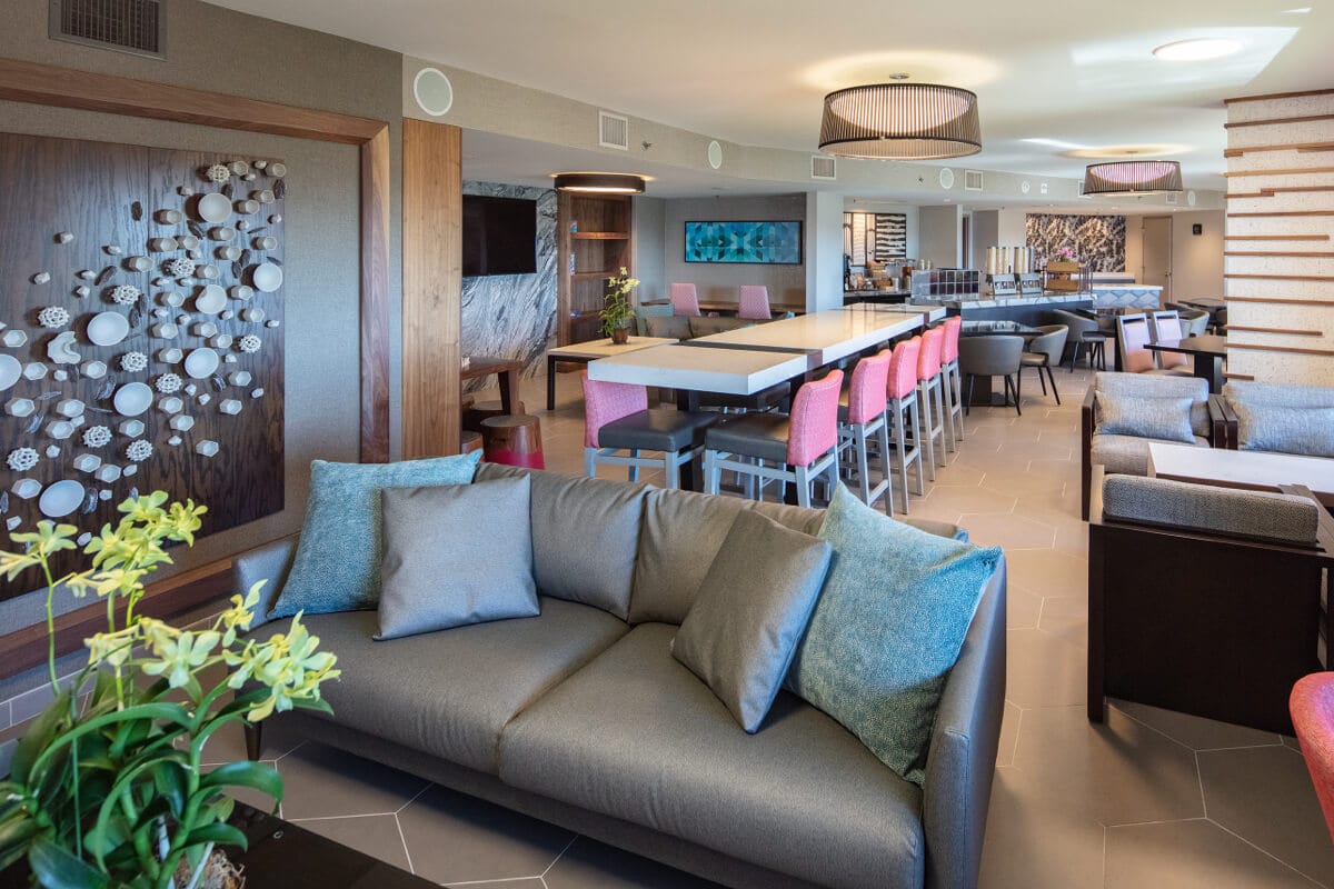A Club Level Room at Loews Royal Pacific Resort with a couch and long table with chairs.