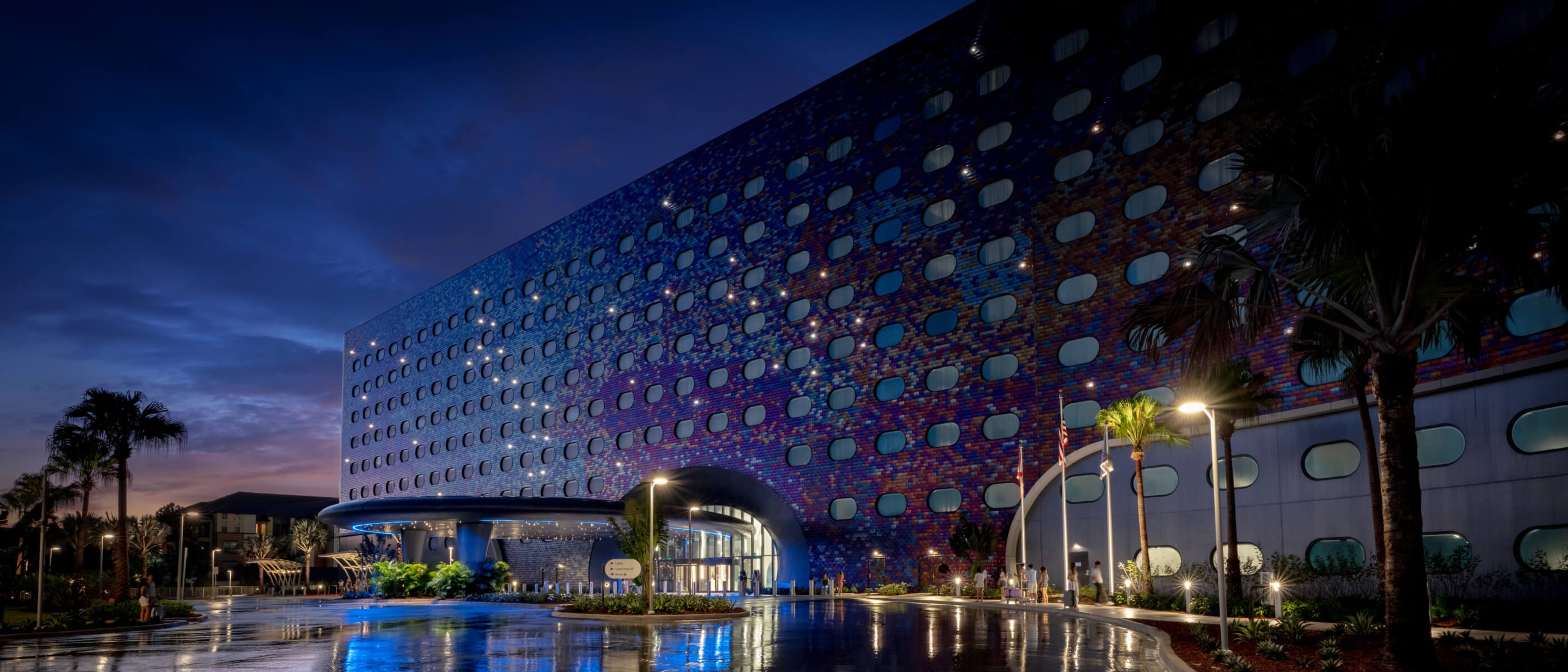 Universal Stella Nova Resort's exterior facade glowing in the moonlight with a sunset in the background.