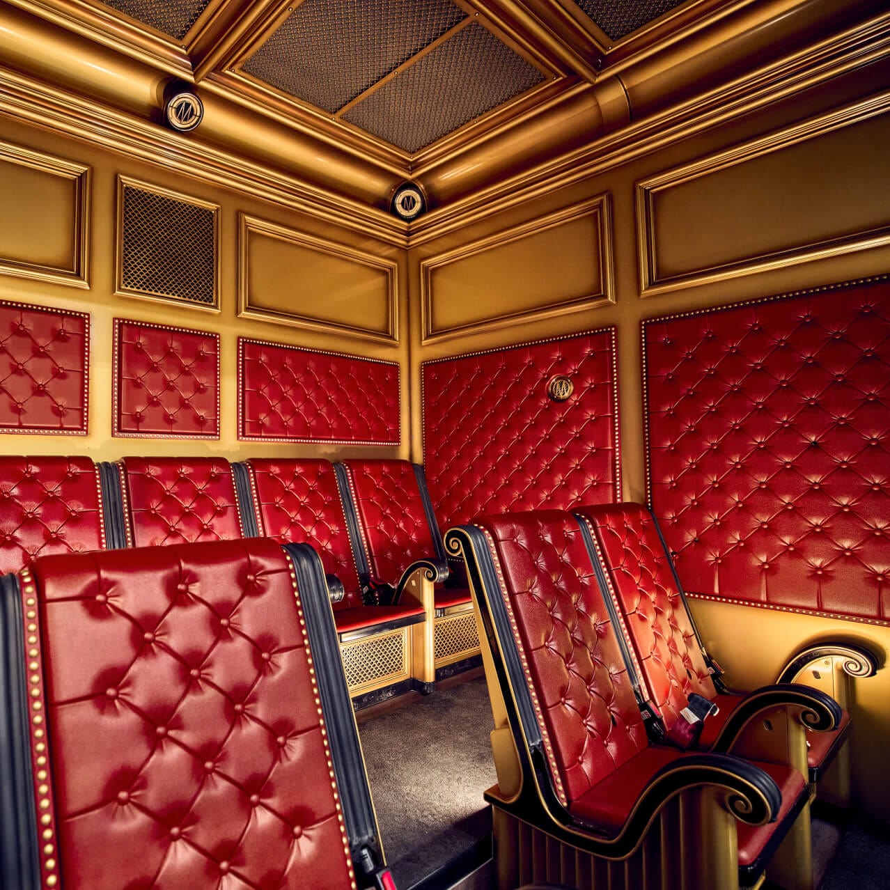A Harry Potter and the Battle at the Ministry™ ride cart, fashioned as theater style seating with red cushioned seats and brass panels.