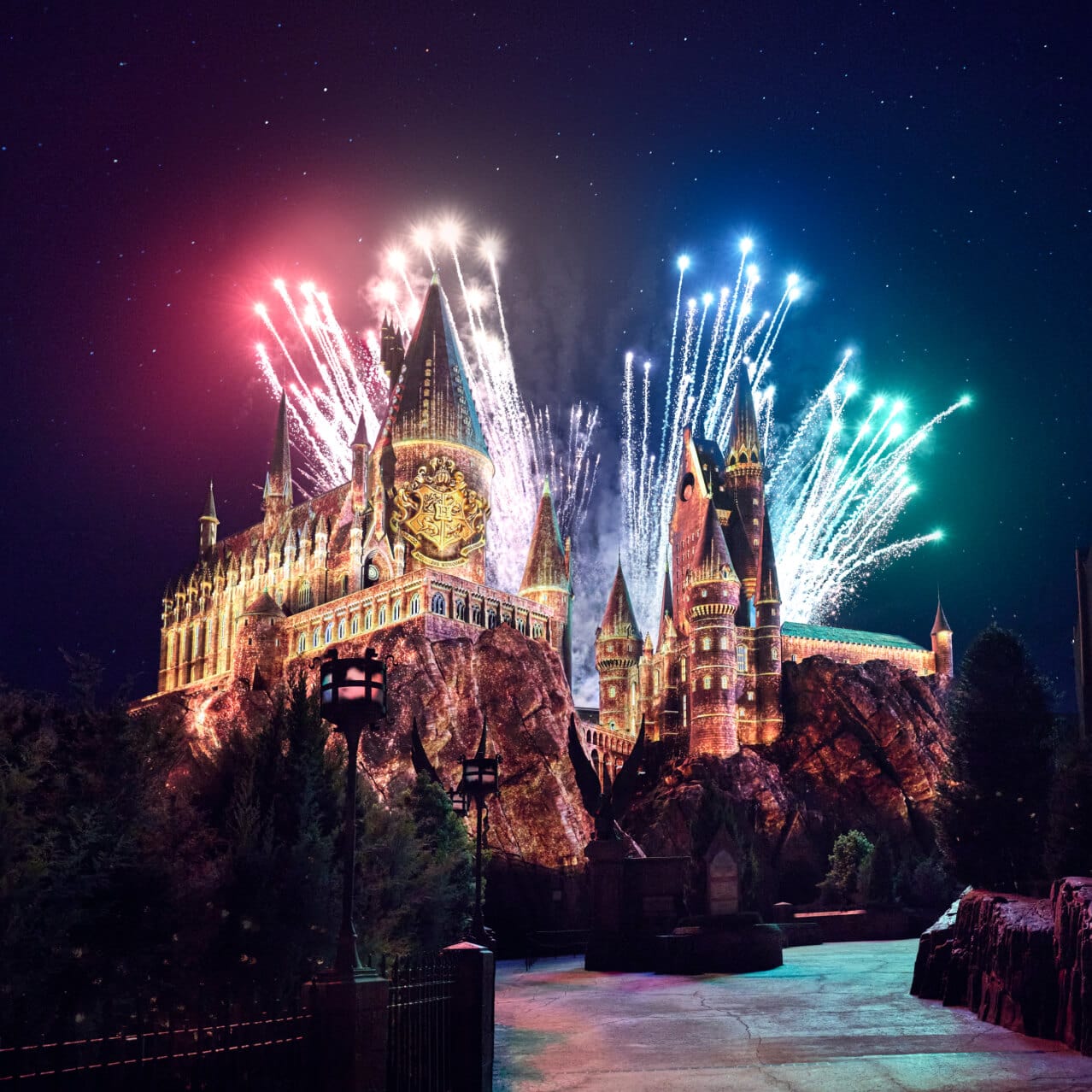 Colorful fireworks lighting up the night sky behind Hogwarts™ at The Wizarding World of Harry Potter™.