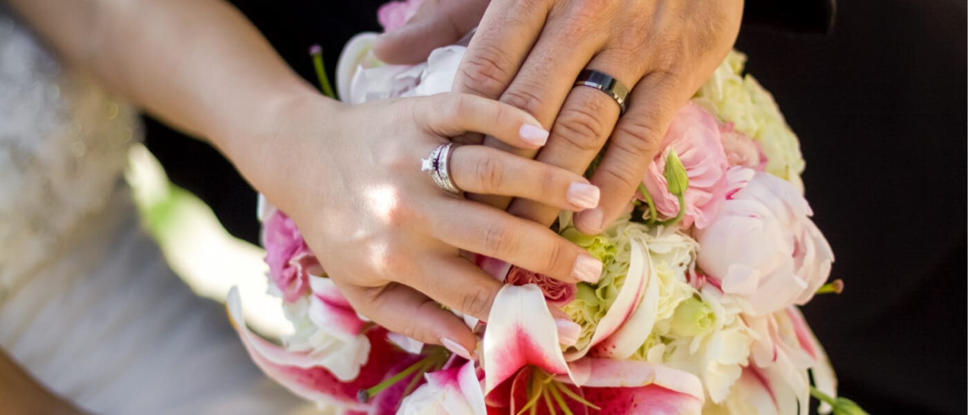 A bride and groom show off their wedding rings and bridal bouquet during a ceremony and reception at Loews Sapphire Falls Resort, a timeless Caribbean themed venue at Universal Orlando Resort.
