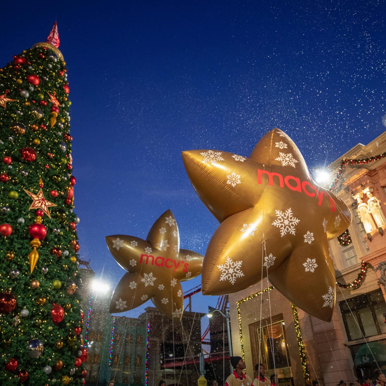 The Macy’s star balloons at Universal Studios Florida pass by a giant decorated holiday tree.