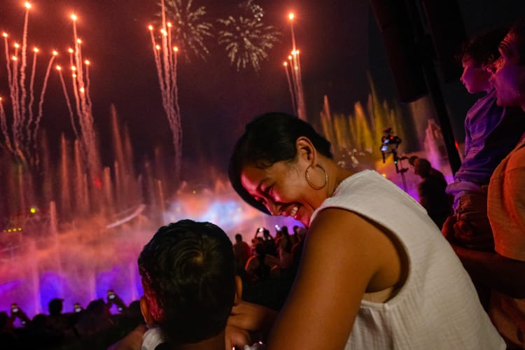 A mother and son embrace while watching the fireworks show at CineSational: A Symphonic Spectacular, featuring Harry Potter, Jurassic World and Jaws.