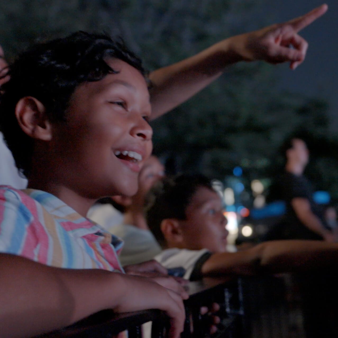 A family smiling with wonder and excitement as they watch a thrilling nighttime show at Universal Orlando Resort.