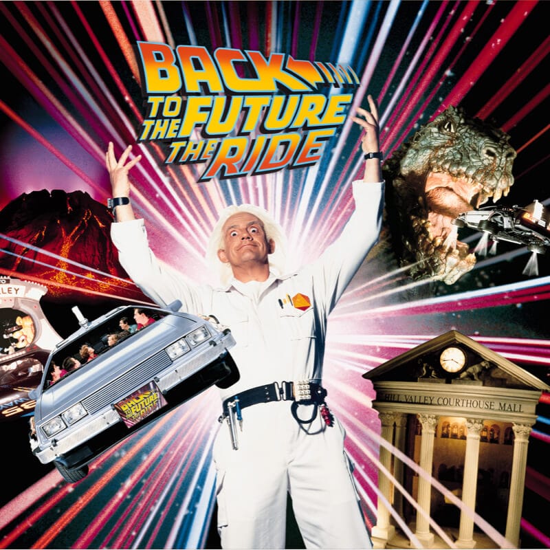 Doc Brown raises his hands next to his time traveling car under the Back to the Future The Ride logo.