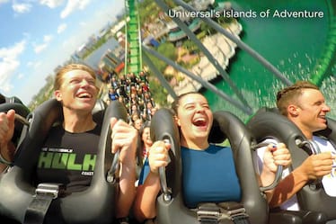 Four young adults scream and laugh while riding in the front row of The Incredible Hulk Coaster at Universal's Islands of Adventure in Orlando.