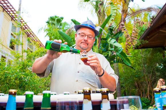 Enjoy a five course meal with unique beer pairings at Jake's Beer Dinner at Loews Royal Pacific Resort. A man pours a bottle of beer into a plastic cup at the Jake's Beer Dinner event at Universal Orlando Resort.