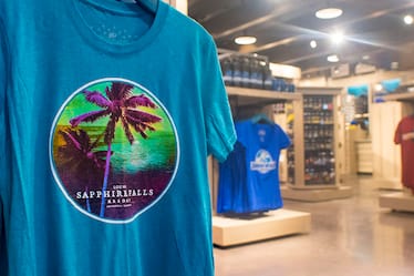 A close-up of a Loews Sapphire Falls Resort T-Shirt with the Universal Studios Store in the background.