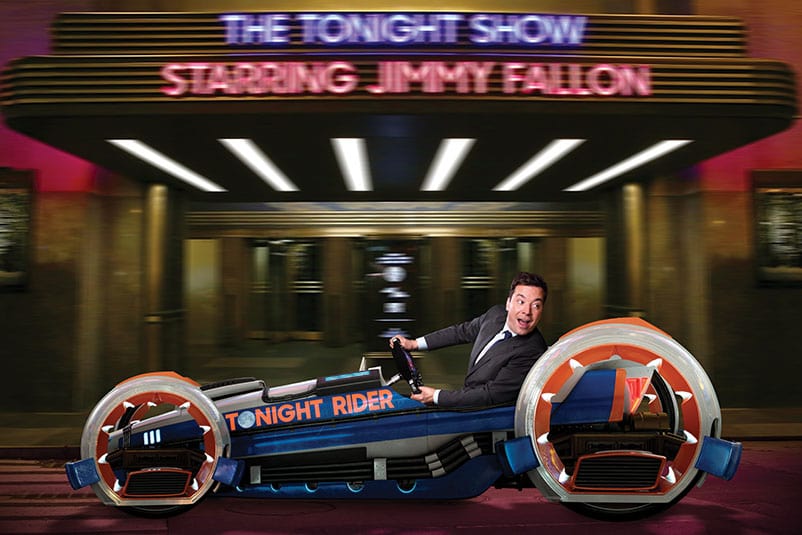 Race Through New York Starring Jimmy Fallon is a new ride coming to Universal Studios Orlando in 2017. Jimmy Fallon looks back over his shoulder as he speeds along in a blue and red hot rod with the words The Tonight Rider on its side in a scene from the Race Through New York Starring Jimmy Fallon attraction at Universal Orlando.