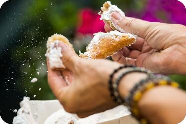 A guest enjoys a beignet at Mardi Gras.