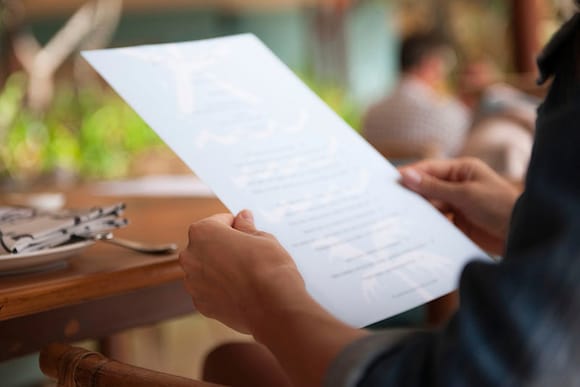 A restaurant guest holds a menu while sitting at a table.