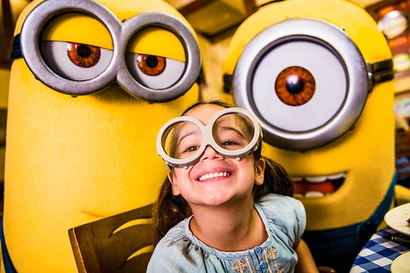 At Universal Orlando, you can dine alongside your favorite theme park character like the Minions from Despicable Me during the Superstar Character Breakfast. A little girl smiles alongside two Minions at the Superstar Character Breakfast at Universal Orlando Resort.