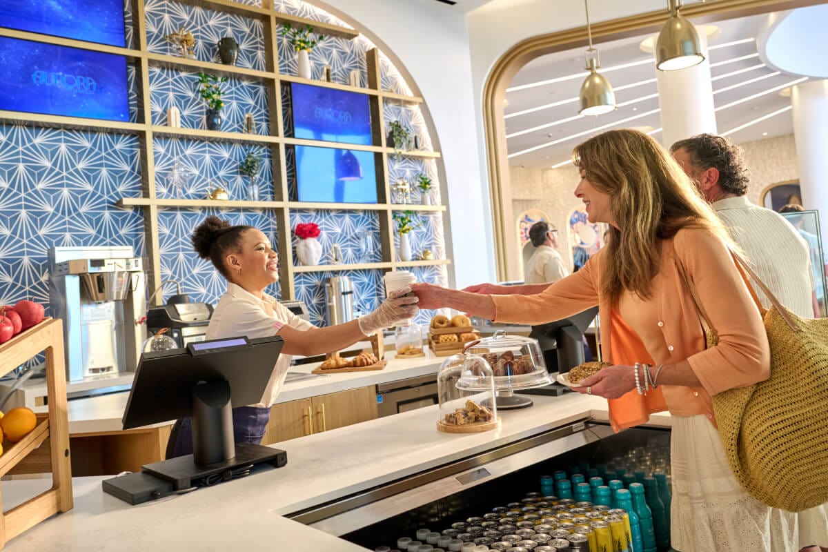 A guest collects her drink from the barista at Aurora Market, inside Universal Helios Grand Hotel. 