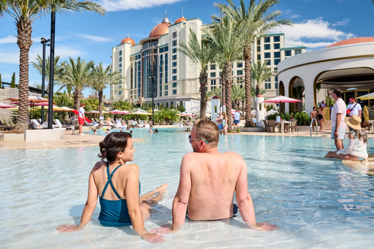 A couple enjoying a soak in the zero-entry pool at Universal Helios Grand Hotel, a Loews Hotel.
