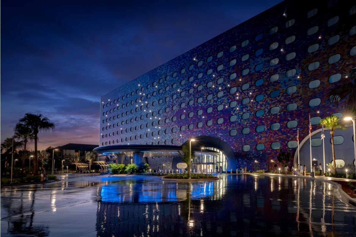 Universal Stella Nova Resort's exterior facade glowing in the moonlight with a sunset in the background.