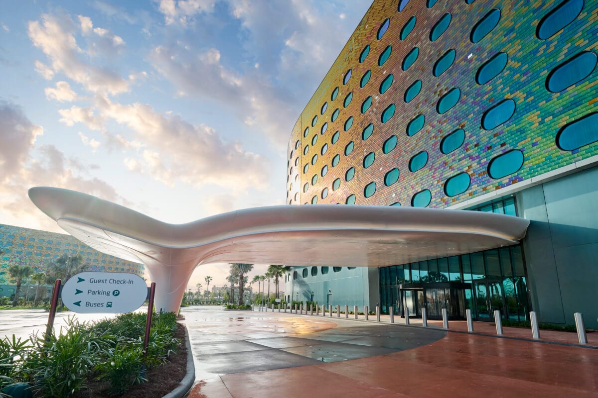 The futuristic-shaped porte-cochere of Universal Terra Luna Resort, with the hotel's facade shimmering in the sunlight.