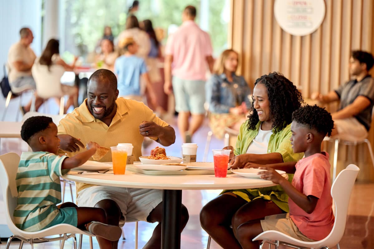 A young family enjoying a meal in the Omega Cafe and Market at Universal Terra Luna Resort.