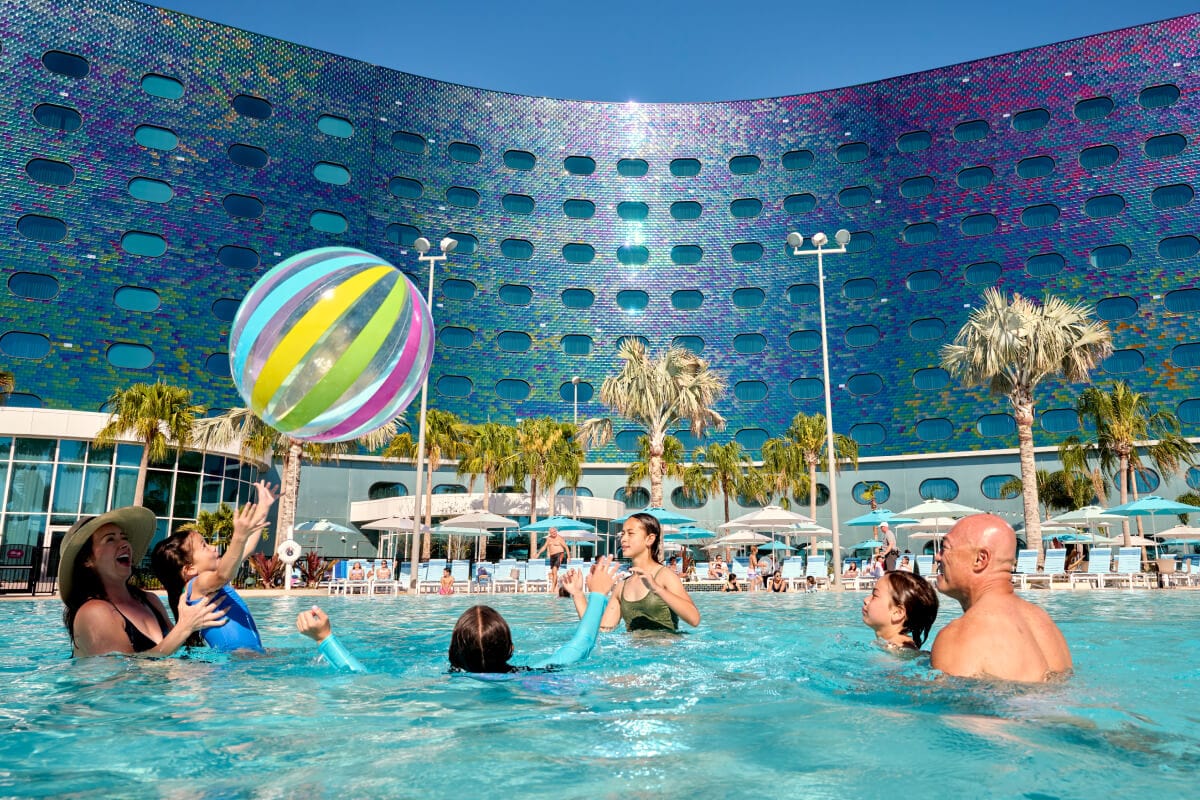 A young family of six play with a giant beach ball in the pool at Universal Terra Luna Resort.