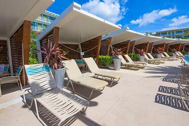 En Universal's Cabana Bay Beach Resort en Orlando, tu puedes rentar una cabana cómoda para una experiencia relajadora al borde de la piscina. Una fila de sillones de playa y cabanas en el área de la piscina en Universal's Cabana Bay Beach Resort en Orlando.