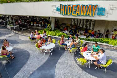 El Hideaway Bar & Grill es un bar conveniente al lado de la piscina ubicado en el Lazy River Courtyard de Cabana Bay Beach Resort en Universal Orlando. Visitantes disfrutan meriendas, comidas y bebidas en las mesas al aire libre en el Hideaway Bar & Grill en Universal Orlando's Cabana Bay Beach Resort.