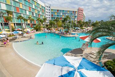 Relájate en comodidad y estilo en el Cabana Bay Beach Resort's Lazy River Courtyard y piscina, donde tu puedes nadar, flotar y jugar. Visitantes en Cabana Bay Beach Resort en Universal Orlando en una piscina y relajándose en el Lazy River Courtyard, donde una piscina sin borde invita a personas de todas edades a disfrutar el sol.