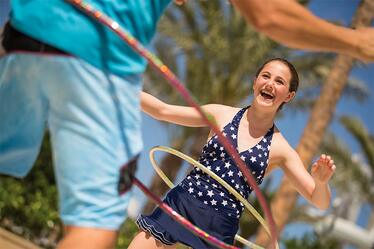 Disfruta juegos en la piscina, incluyendo hula hoops y competencias de salpiques y películas al aire libre, en Cabana Bay Beach Resort en Universal Orlando. Dos niños juegan con hula hoops en el área de la piscina de Cabana Bay Beach Resort en Universal Orlando.