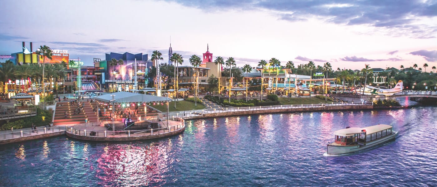 Vista del horizonte de Universal CityWalk en contraste con la laguna mientras un taxi acuático pasa por las aguas.