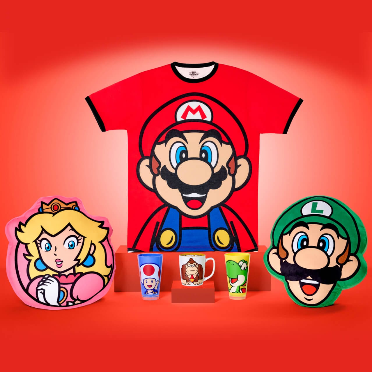 Productos de personajes de Nintendo™, incluida una camiseta de Mario, almohadas de la Princesa Peach y Luigi, vasos de Toad y Yoshi y una taza de Donkey Kong de SUPER NINTENDO WORLD™.