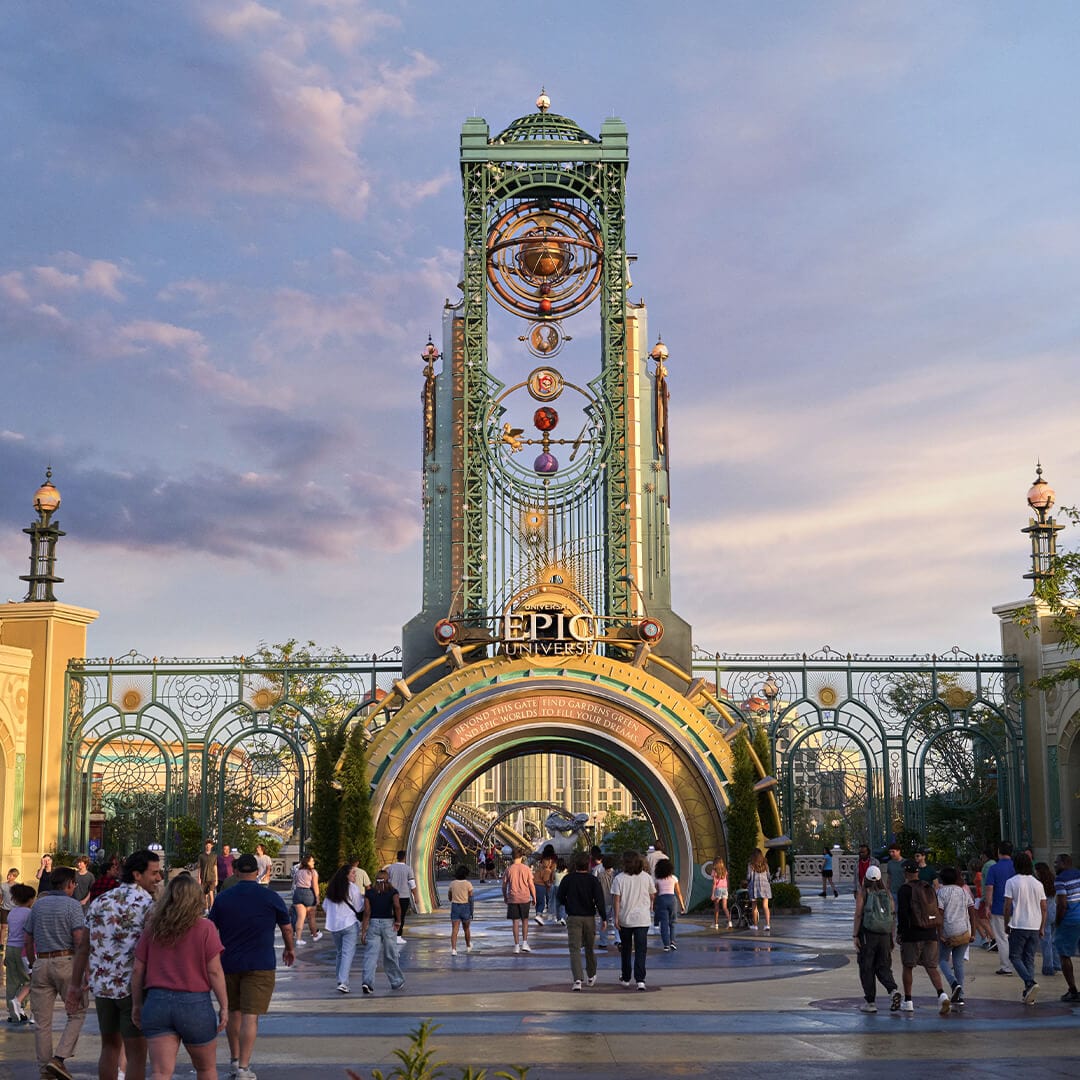 Visitantes caminan hacia el portal de Celestial Park en la entrada principal de Universal Epic Universe, con Chronos elevándose sobre ellos.
